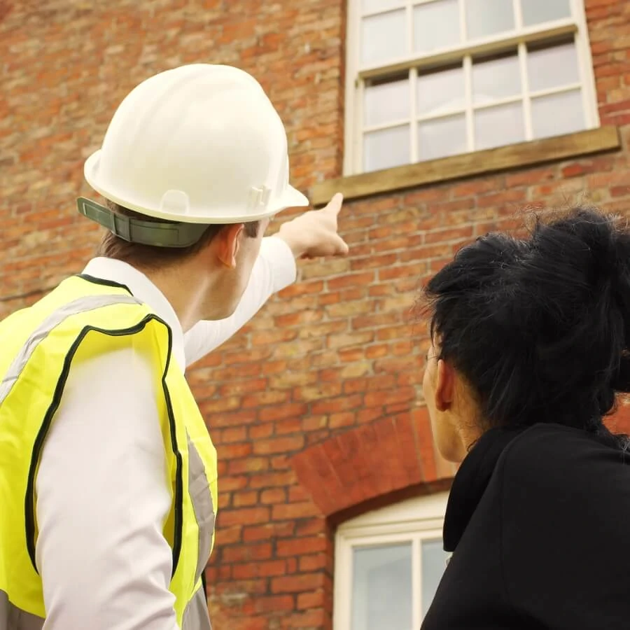 Retrofit professional assessing a brick property with a client